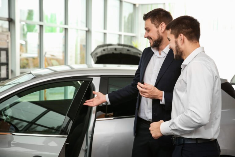 Handsome,Car,Salesman,With,Trainee,Looking,At,Automobile,In,Dealership